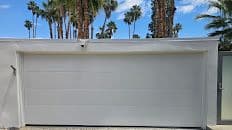 Freshly painted white garage door with palm trees in the background